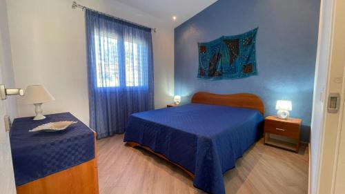 ein Schlafzimmer mit einem blauen Bett und einem Fenster in der Unterkunft Villa Corallo - Scopello Guidaloca Bay in Scopello
