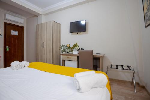 a bedroom with a bed and a desk and a television at Daisi Sunset Hotel in Batumi