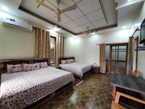 um quarto com 2 camas e uma ventoinha de tecto em Bora's Homestay em Haldwani