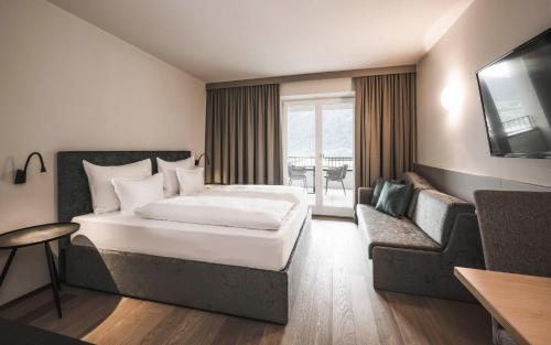 a hotel room with a bed and a couch at SomVita Suites in Tirolo
