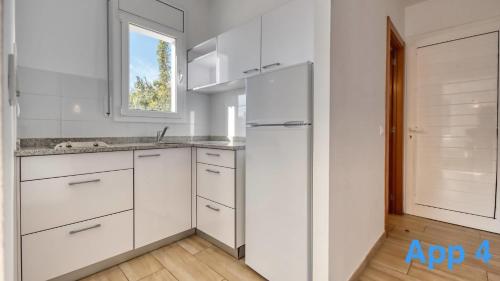 a kitchen with white cabinets and a refrigerator at Costacabana - Villa Pilar in Lloret de Mar