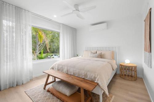 a white bedroom with a bed and a window at Vibes At Five Noosa in Noosaville