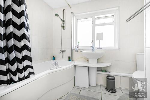 a white bathroom with a sink and a bath tub and a sink at Lux Homes in Sunbury Common