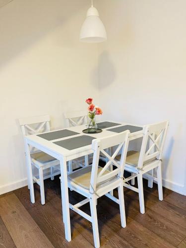 a white table with chairs and a vase with flowers at Scandinavian Apartment Hotel - Lunden 1 - Central 3 bedroom apartment on two floors in Horsens