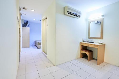 ein Badezimmer mit einem Waschtisch, einem Spiegel und einem Tisch in der Unterkunft Tang City Hotel at Petaling Street in Kuala Lumpur
