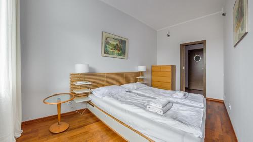 a bedroom with a white bed and a table at Apartamenty Sun & Snow Redłowo in Gdynia