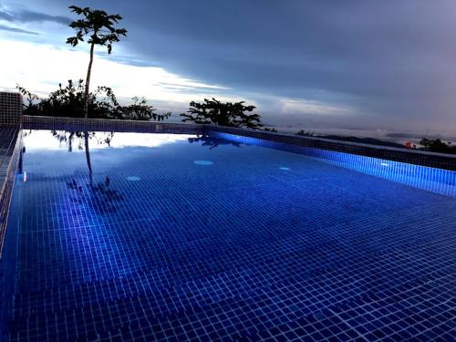 Villa La Vista of Panama City and magestical mountains from infinity pool في سيرو أزول: مسبح ازرق كبير مع شجرة في الخلفية