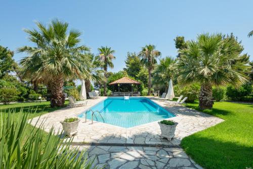 a swimming pool in a yard with palm trees at Coconut & Vanilla & Pineapple Pool Apartments #FeelsLikeHome in Kriopigi
