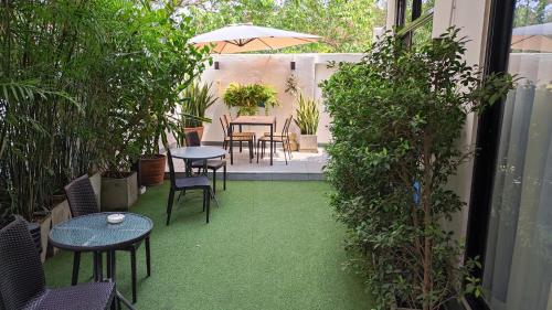 eine Terrasse mit Tischen, Stühlen und grünem Gras in der Unterkunft Hotel Montha in Chiang Mai