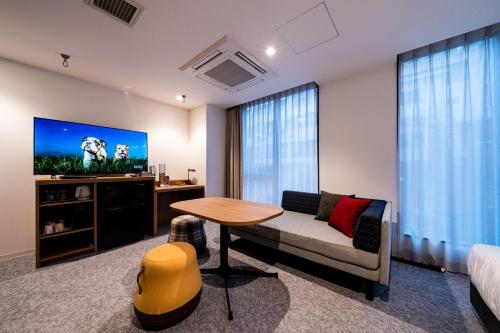 a living room with a couch and a table and a tv at Bay Hotel Tokyo Hamamatsucho in Tokyo
