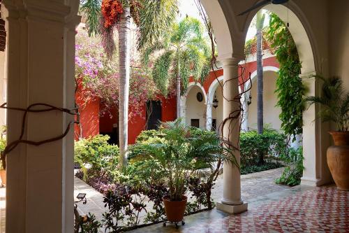 a courtyard with palm trees and plants in a building at VILLA MERIDA BOUTIQUE HOTEL - Adults Only in Mérida