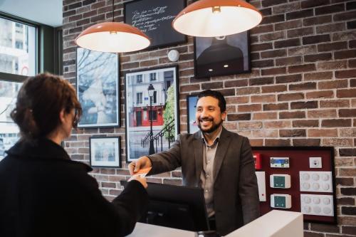 Um homem a apertar a mão a uma mulher num café. em easyHotel Paris Nord Aubervilliers em Aubervilliers