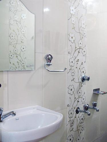 a white bathroom with a sink and a mirror at Gladsvilla in Mangalore