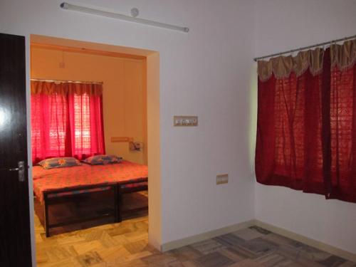 a bedroom with a bed with red curtains at Gladsvilla in Mangalore