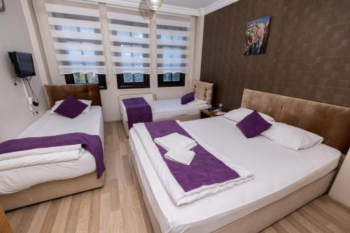 two beds in a room with purple and white sheets at SULTAN SARAY OTEL in Safranbolu