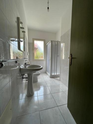 een badkamer met een wastafel, een toilet en een spiegel bij Casa Mario e Rosa in Orosei