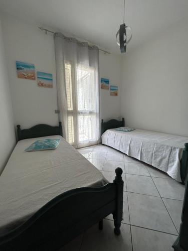 een slaapkamer met twee bedden en een raam bij Casa Mario e Rosa in Orosei