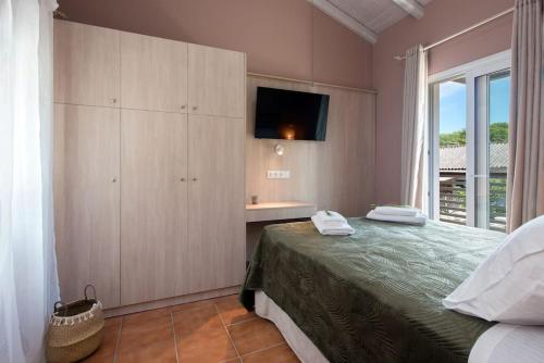 um quarto com uma cama, uma televisão e uma janela em Nikas Guest House em Kanálion