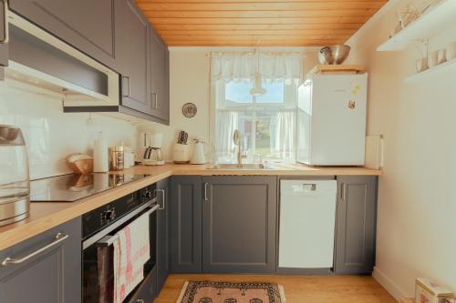 a kitchen with gray cabinets and a white refrigerator at Lovely 4-BR house / Sea view / Nature in Oyndarfjørður