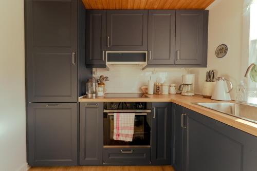 a kitchen with dark gray cabinets and a sink at Lovely 4-BR house / Sea view / Nature in Oyndarfjørður