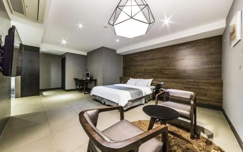 1 dormitorio con 1 cama, mesa y sillas en Cherbourg Hotel, en Gwangmyeong