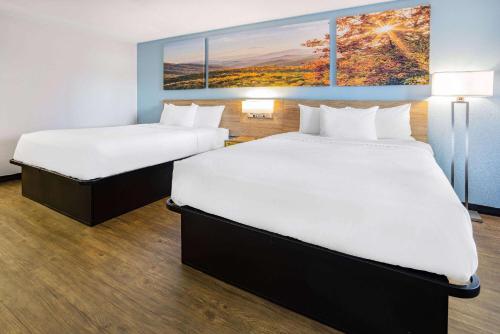 a hotel room with two beds and a painting on the wall at Days Inn by Wyndham Raleigh Glenwood-Crabtree in Raleigh