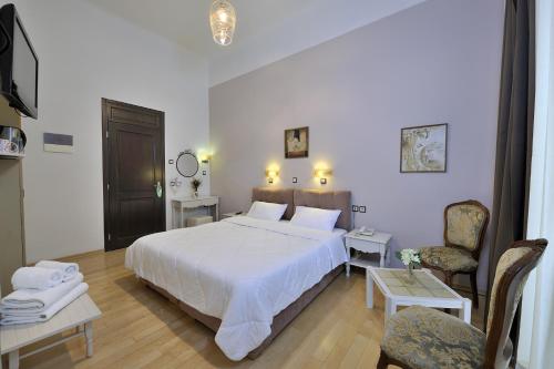 a bedroom with a large white bed and two chairs at Dryades & Orion Hotel in Athens