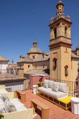 un toit-terrasse avec des canapés et une tour d'horloge dans l'établissement New! Ohliving San Bernardo, à Séville