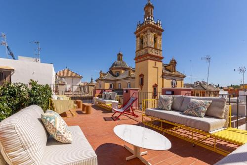 eine Terrasse mit Sofas, Tischen und einem Uhrturm in der Unterkunft New! Ohliving San Bernardo in Sevilla