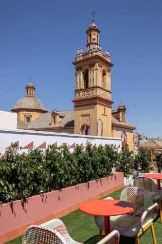um pátio com mesas e cadeiras e uma torre do relógio em New! Ohliving San Bernardo em Sevilha