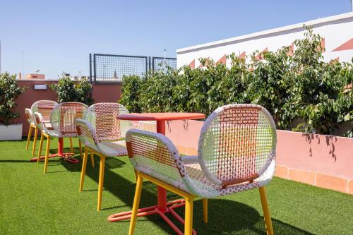 a row of chairs and a table on the grass at New! Ohliving San Bernardo in Seville