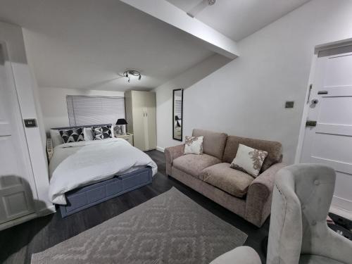 ein Schlafzimmer mit einem Bett und einem Sofa in der Unterkunft Studio 2 min walk to Upton Park Station in London