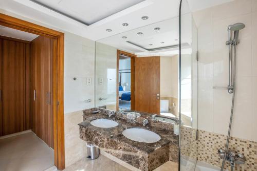 a bathroom with two sinks and a glass shower at VayK - Modern Four Bedroom with Sea View in Dubai Marina in Dubai