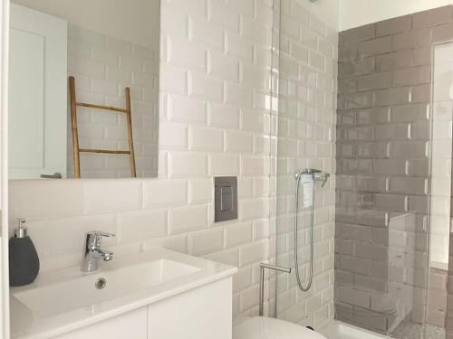 a white bathroom with a shower and a sink at Casa da Oliveira in Évora