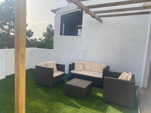 un patio con 2 sillas, un sofá y una mesa en Villa LA RAMA DEL DRAGO, Agaete, en San Pedro