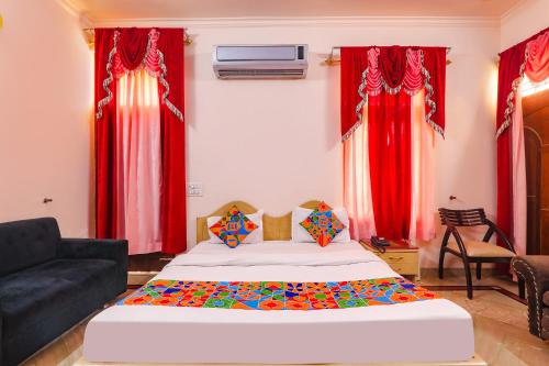 a bedroom with a bed and a couch and red curtains at FabHotel Raka Inn in Allahābād