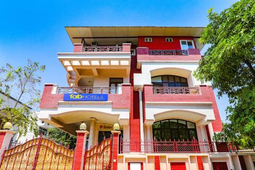 a red and white building with a blue sign on it at FabHotel Raka Inn in Allahābād