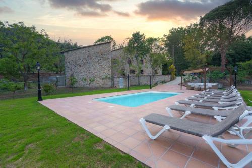 a group of lounge chairs next to a swimming pool at Masía Can Janet in Arbúcies