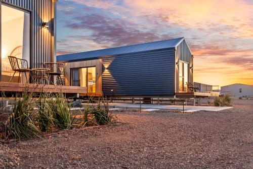 a small house with a black roof and a table at Three Ponds Estate in Temora