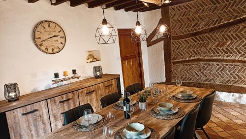 a dining room with a table and a clock on the wall at Gite : Le vi colombage de Petites-Tailles in Vielsalm