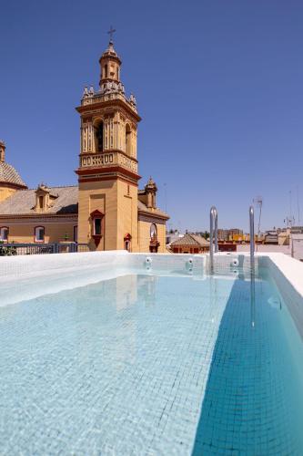 une piscine en face d'un bâtiment avec une tour d'horloge dans l'établissement New! Ohliving San Bernardo, à Séville