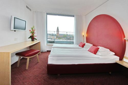 a hotel room with two beds and a desk and a window at ARCOTEL Rubin Hamburg in Hamburg