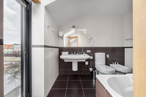 een badkamer met 2 toiletten, een wastafel en een bad bij Euterpe Hotel in Klaipėda