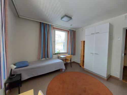 a bedroom with a bed and a desk and a window at Hostel Teopolis in Tampere