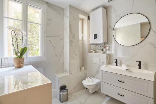 a white bathroom with a sink and a mirror at Apartment Parc des expositions by Studio prestige in Paris