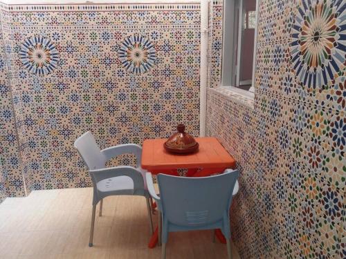 einen Tisch und Stühle in einem Zimmer mit bunten Fliesen in der Unterkunft Oisis Mazagan 2 in El Jadida