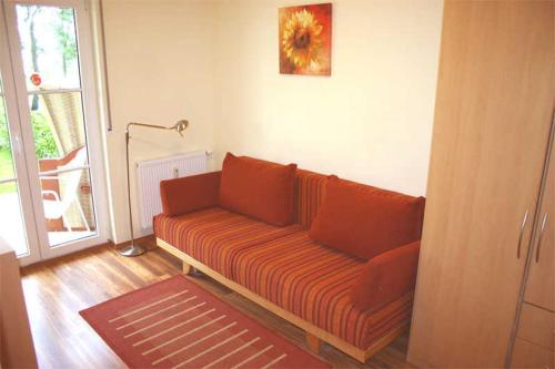 an orange couch in a living room with a window at Landhaus zum Strande - 44-6 1 in Kägsdorf