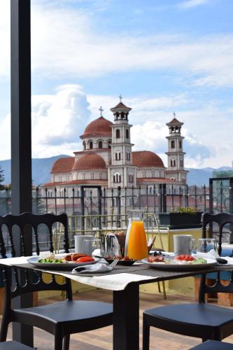 einen Tisch mit Speisen und Getränken auf einem Balkon mit einem Gebäude in der Unterkunft Bocca Hotel Korce in Korçë