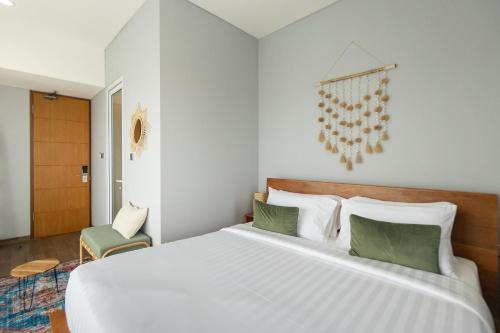 een slaapkamer met een groot wit bed met groene kussens bij Sarang Comfort in Canggu