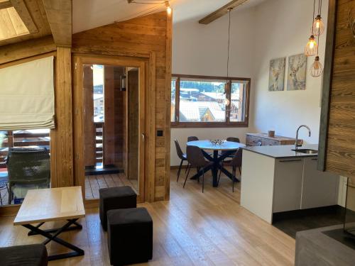 a kitchen and living room with a table and chairs at Le Lodge Chasse Montagne in Les Gets
